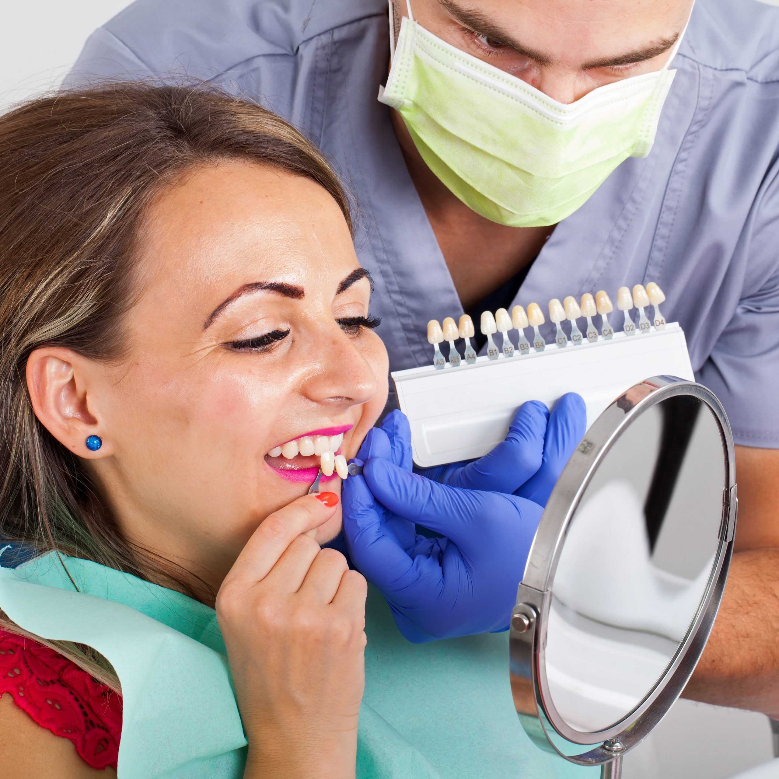 Dental shade determination with shade guide. Female patient wearing pink lipstick close up