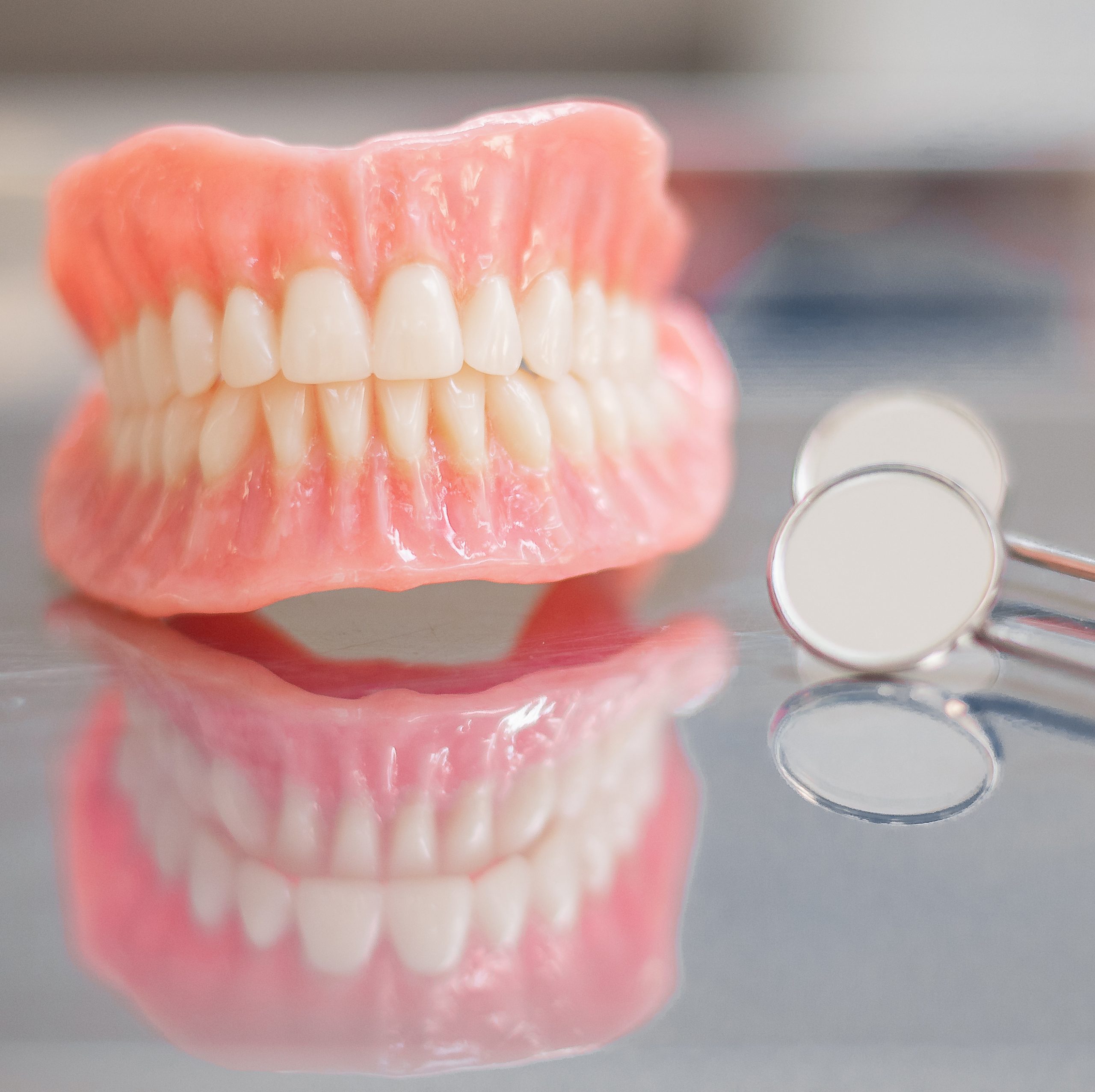 Two dentures. Instruments and dental hygienist checkup concept with teeth model dentures and mouth mirror. Regular dentist checkups